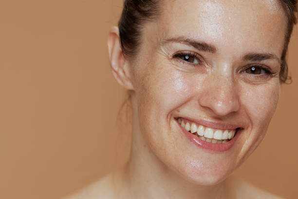 happy young woman with wet face washing isolated on beige background.